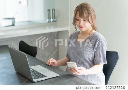 A young pregnant woman uses a pregnancy diary, pregnancy record, and maternal and child record book app on a smartphone or laptop. 112127328