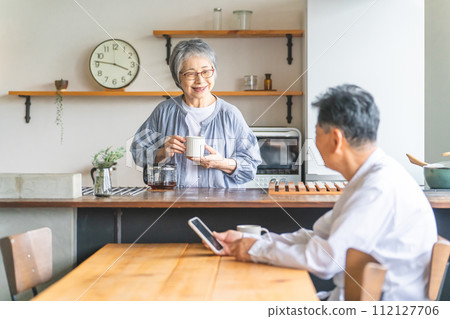 A senior couple smiling and talking while drinking coffee in the dining kitchen of their home A senior couple smiling and talking while drinking coffee in the dining kitchen of their home 112127706