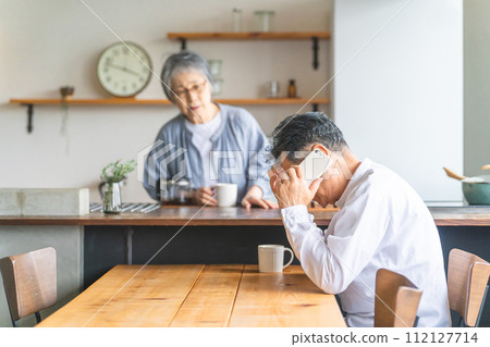 Elderly man having trouble while calling on smartphone at home (apologizing, shocked, deceived, worried) 112127714