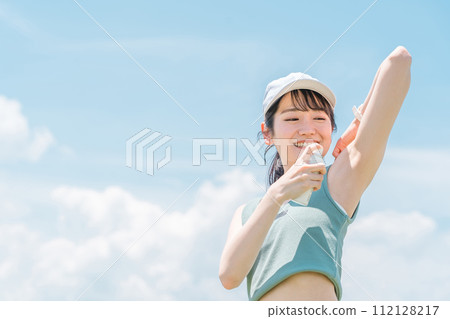 A woman using antiperspirant spray while exercising, walking, or jogging outside (armpit/deodorant) 112128217