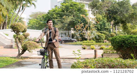 The businessman eco friendly transportation, cycling through the city avenues to go to work. sustainable lifestyle concept The businessman eco friendly transportation, cycling through the city avenues to go to work. sustainable lifestyle concept 112128702