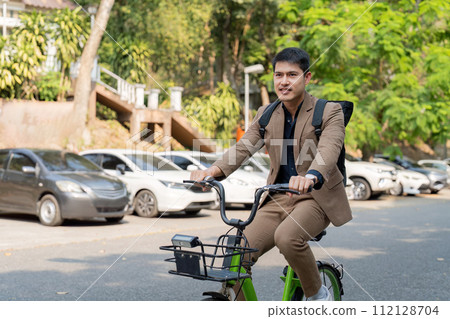 The businessman eco friendly transportation, cycling through the city avenues to go to work. sustainable lifestyle concept The businessman eco friendly transportation, cycling through the city avenues to go to work. sustainable lifestyle concept 112128704