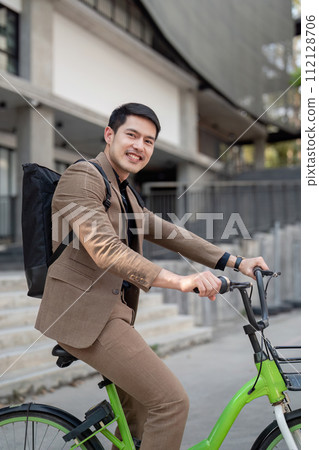 The businessman eco friendly transportation, cycling through the city avenues to go to work. sustainable lifestyle concept The businessman eco friendly transportation, cycling through the city avenues to go to work. sustainable lifestyle concept 112128706
