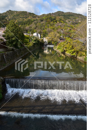 日本春天的京都,嵐山周圍的街道,桂川,旅遊勝地,盛開的櫻花和美麗的新綠,河邊的老房子 日本春天的京都,嵐山周圍的街道,桂川,旅遊勝地,盛開的櫻花和美麗的新綠,河邊的老房子 112128728