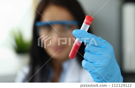 Female hand in blue protective gloves holding test tube 112129122