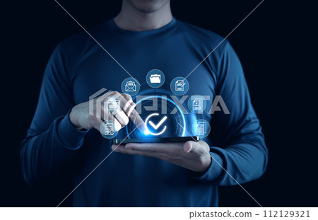 Online approval paperless and quality assurance concept. Businessman using smartphone with virtual correct sign or tick mark with document icon for approve, Quality assurance and guarantee. 112129321