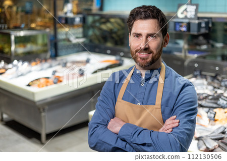 Portrait of a confident and experienced male shop worker, proudly standing in the seafood department of a supermarket. His friendly smile and professional apron suggest expertise and approachability Portrait of a confident and experienced male shop worker, proudly standing in the seafood department of a supermarket. His friendly smile and professional apron suggest expertise and approachability 112130506