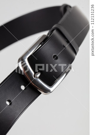 Part of a black leather classic belt with a buckle on a gray background. Part of a black leather classic belt with a buckle on a gray background. 112131236