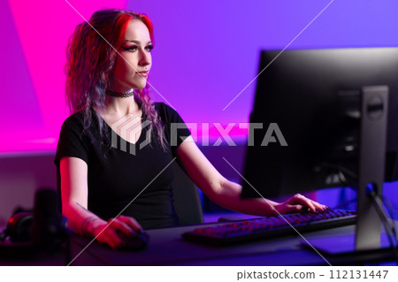 Focused Female Gamer Playing in a Vibrant Gaming Room Focused Female Gamer Playing in a Vibrant Gaming Room 112131447
