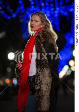Portrait of a beautiful middle-aged woman in an evening winter city. 112131776