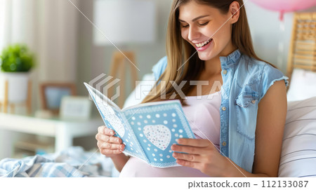 Happy young pregnant woman reading while lying in bed. Waiting for the baby 112133087