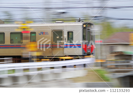 A local train (Kiha 126 series diesel railcar) passing through a railroad crossing at high speed 112133293