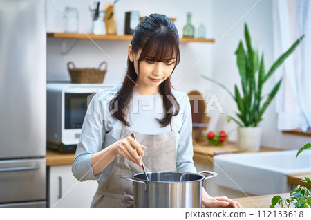 圍裙的年輕主婦在廚房裡做飯 112133618
