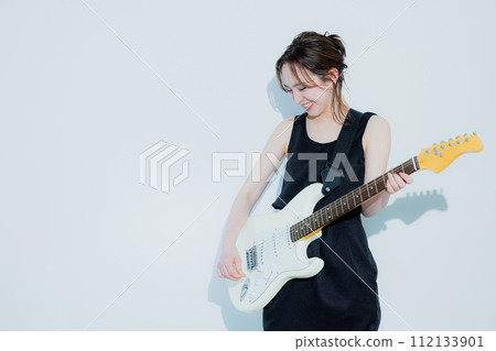 A woman playing an electric guitar 112133901