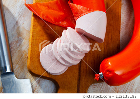 Mortadela sausage cut in slices on a wooden surface 112135182