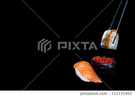 sushi on a black background, sushi nigiri, caviar and sushi with eel taken with chopsticks sushi on a black background, sushi nigiri, caviar and sushi with eel taken with chopsticks 112135403