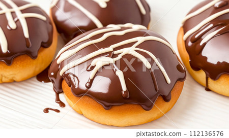 Baked Buns with chocolate glaze on white table. Chocolate bun, pastries or dessert with chocolate cream 112136576