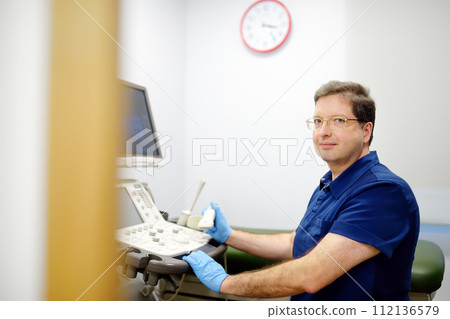 Portrait of oncologist mammologist doctor during appointment of patient. Doctor of ultrasound scanning during working in modern clinic. Portrait of oncologist mammologist doctor during appointment of patient. Doctor of ultrasound scanning during working in modern clinic. 112136579