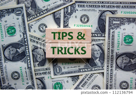 Tips and tricks symbol. Wooden blocks with words 'Tips and tricks'. Beautiful background from dollar bills. Business, tips and tricks concept. Copy space. Tips and tricks symbol. Wooden blocks with words 'Tips and tricks'. Beautiful background from dollar bills. Business, tips and tricks concept. Copy space. 112136794