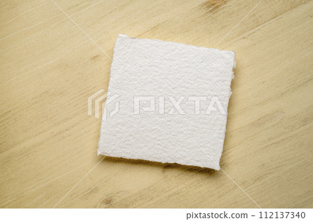 small, square, blank sheet of watercolor paper against wooden background 112137340