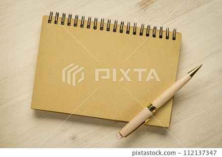 blank spiral notebook with a luxury pen against wooden background 112137347