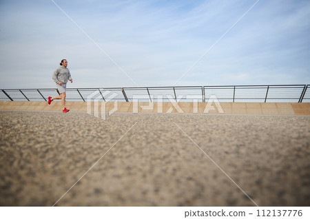 Fit man burning calories during morning jog, enjoying workout outdoor. People. Sport. Active healthy lifestyle concept. Fit man burning calories during morning jog, enjoying workout outdoor. People. Sport. Active healthy lifestyle concept. 112137776