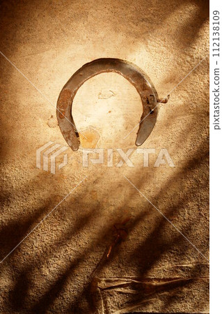 A rusty horseshoe is on a wall 112138109