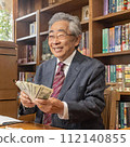 An elderly Japanese man is happily counting money. 112140855