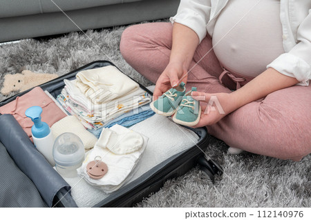 Expecting mother holding tiny baby shoes. Maternity prenatal care concept 112140976