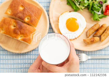 Hands of a woman eating breakfast of milk and bread Hands of a woman eating breakfast of milk and bread 112142336