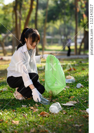 Shot of young lady collecting plastic bottles, cleaning up nature. Charity and ecology concept 112143027