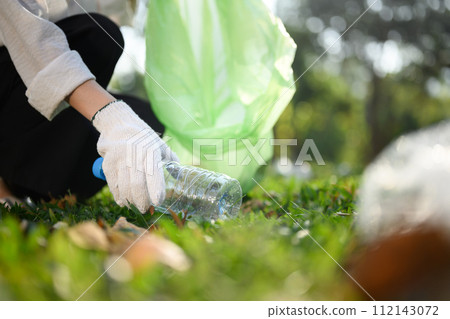 Closeup young woman hand collecting plastic bottles, cleaning up nature. Charity and ecology concept 112143072
