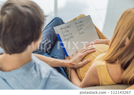 Expectant couple joyfully selects a name for their unborn daughter, savoring the special moment of choosing a meaningful identity for their growing family 112143267