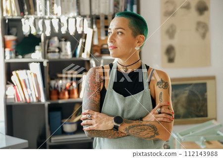 Creative female worker standing with crossed hands on background of design studio Creative female worker standing with crossed hands on background of design studio 112143988