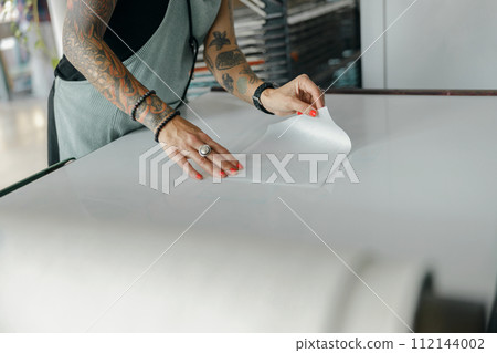 Close up of female worker preparing screen printing film for using on printing machine in a workshop 112144002