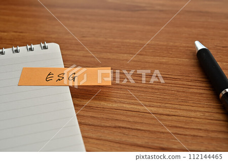 一張寫有 ESG 的便利貼、一本筆記本和一支筆 一張寫有 ESG 的便利貼、一本筆記本和一支筆 112144465