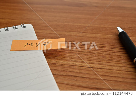 一張寫有 MVP 的便利貼、一本筆記本和一支筆 一張寫有 MVP 的便利貼、一本筆記本和一支筆 112144473