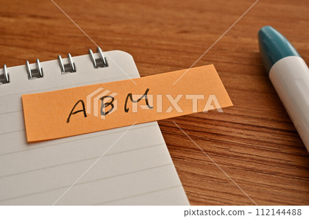 一張寫有 ABM 的便利貼、一本筆記本和一支筆 一張寫有 ABM 的便利貼、一本筆記本和一支筆 112144488