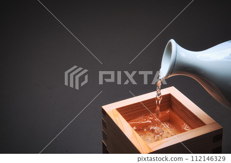 Pour sake into a wooden box 112146329