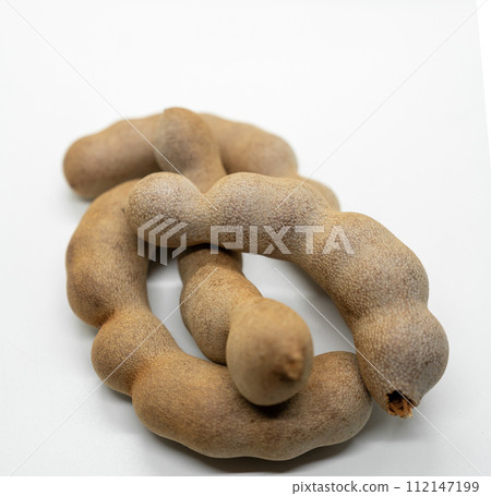 Close-up image of intertwined brown tamarind pods isolated on a white background.. Close-up image of intertwined brown tamarind pods isolated on a white background.. 112147199