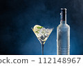 Vodka Cocktail glass and ice-cold bottle on blue degraded background with copy space. 112148967