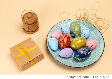 Dish with colored Easter eggs and a gift box. 112149266
