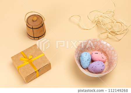 Bowl with colored Easter eggs and a gift box. Bowl with colored Easter eggs and a gift box. 112149268