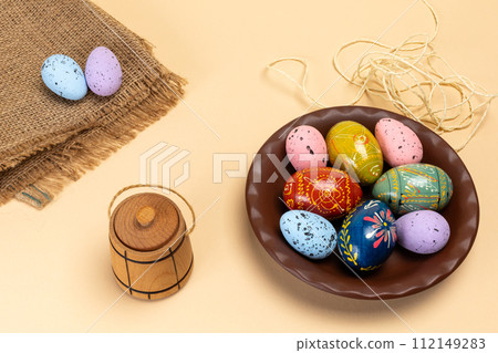 Plate with colored Easter eggs and a sackcloth bag. 112149283
