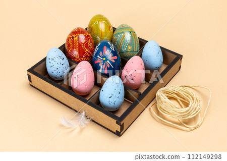 Colorful Easter eggs in a box on the beige background. Colorful Easter eggs in a box on the beige background. 112149298