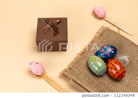 Colored Easter eggs on a sackcloth bag and a gift box. 112149349