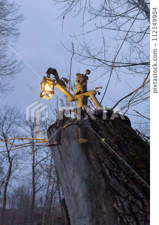 a wooden figure of a forester with a lantern on a tree 112149984