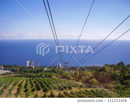 Breathtaking mountain views: Cable car ascends a lush hillside, with a panoramic ocean view below Breathtaking mountain views: Cable car ascends a lush hillside, with a panoramic ocean view below 112151836