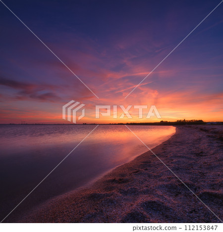 A seascape during sunset. Seashore and cloudy sky background. Bright sky during sunset. 112153847