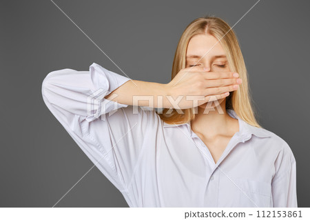 Young woman covers her mouth with her palm Young woman covers her mouth with her palm 112153861